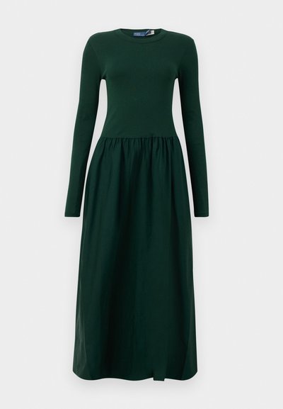 Long-sleeve, dark green dress with a fitted top and flowy, gathered skirt. Made from soft fabric with a round neckline and ankle length.