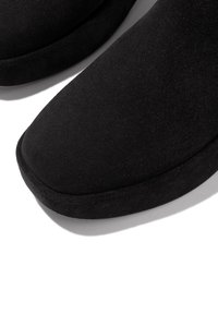 Zwarte leren pantoffels van suede met een ronde, brede teenbox en een zachte textuur. De zool is gevoerd, wat comfort en warmte biedt.