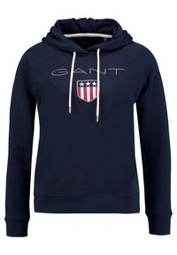 Sudadera con capucha en color navy con un logotipo frontal que presenta un diseño de escudo, tres estrellas y franjas. Cuenta con cordones y puños acanalados.