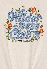 Beige bomulds skjorte med et farverigt grafik med teksten "Wilderness Club" i blå, prydet med blomster og en kanin illustration.