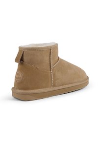 Beżowe zamszowe botki za kostkę z białym futrem, z zaokrąglonym logo, przeszyciami i płaską gumową podeszwą.