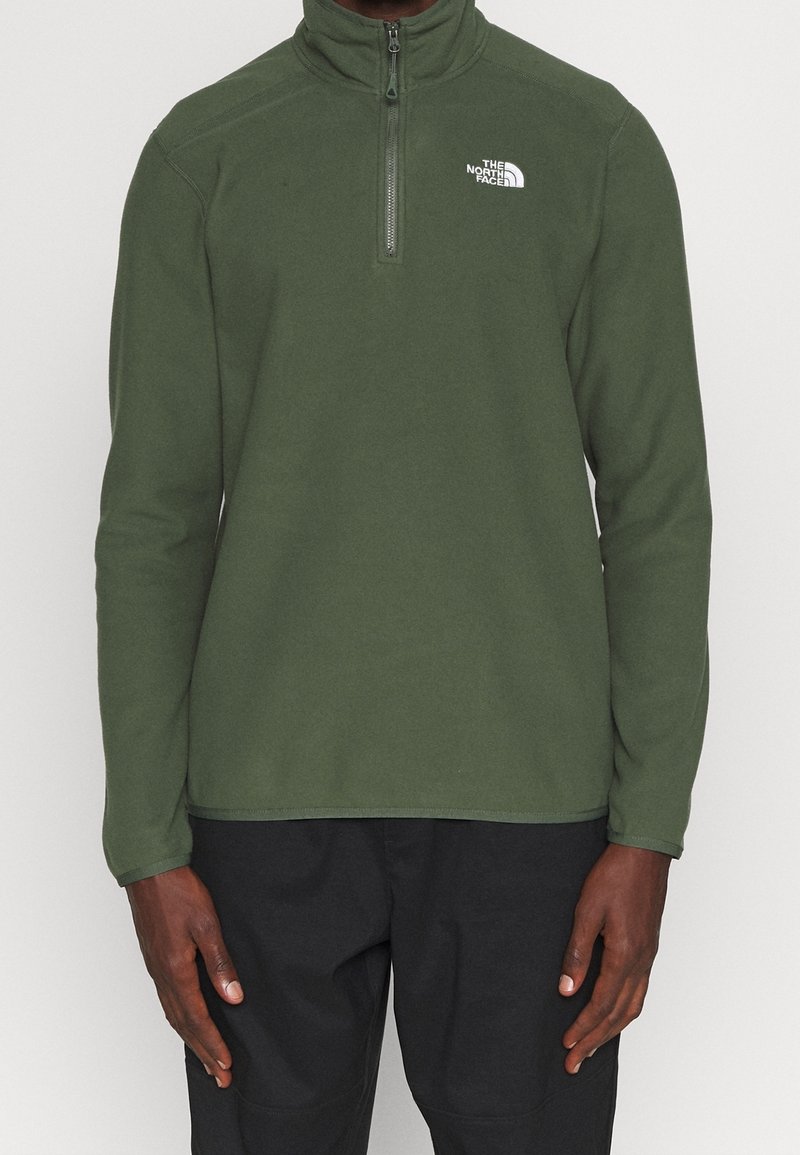 Grüner Fleece-Pullover mit halbem Reißverschluss und langen Ärmeln. Mit kleinem weißem Logo auf der linken Brust. Glatte Textur.