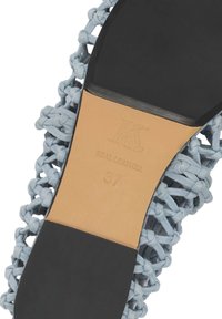 Semelle d'une chaussure tissée en cuir bleu clair montrant un centre lisse de couleur beige avec la pointure 37 et l'inscription "Cuir véritable" en relief, entourée par des zones noires pour le talon et l'orteil.