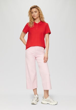 Rode polo shirt met een kraag en knopenlijst, gecombineerd met lichtroze wijde broek en beige sneakers. Soepele textuur, casual pasvorm.