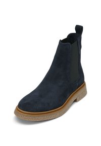 Botín de ante azul marino con paneles laterales elásticos. Cuenta con una suela de goma texturizada y un tirador para facilitar su uso. Diseño clásico de chelsea.
