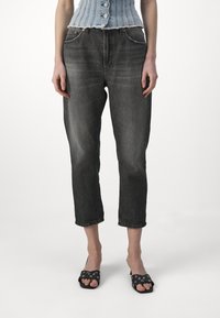 Jeans neri tagliati con una finitura sbiadita, design a cinque tasche e orlo grezzo. Indossati con sandali neri aperti davanti con tagli circolari.
