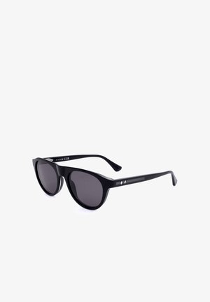 Occhiali da sole con montatura a occhi di gatto neri, lenti scure e sottili dettagli a diamante in argento sulle stanghette, inclinati su uno sfondo bianco.