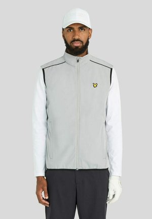 Man draagt een wit shirt met lange mouwen, lichtgrijs mouwloos jasje met een klein geel logo, zwarte broek, witte pet en een witte golfhandschoen aan de rechterhand.