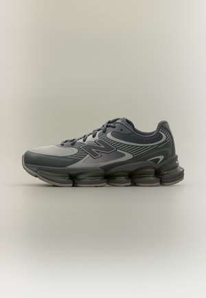 Тъмносив спортен маратон New Balance с многослойни мрежести панели, черни връзки и сегментирана омекотена подметка, показан в профил.