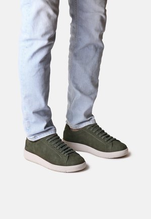 Green suede sneakers with a low-top design, featuring a textured surface and white rubber sole, laced up with matching green shoelaces.