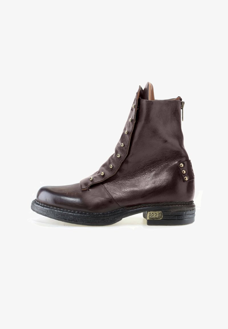 Bottine en cuir marron foncé avec rabat déboutonné montrant des œillets métalliques et un talon bas empilé avec une petite plaque métallique sur le côté extérieur.
