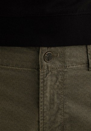 Primer plano de pantalones kaki con textura, con una cinturilla negra y un botón con marca asegurado al frente.