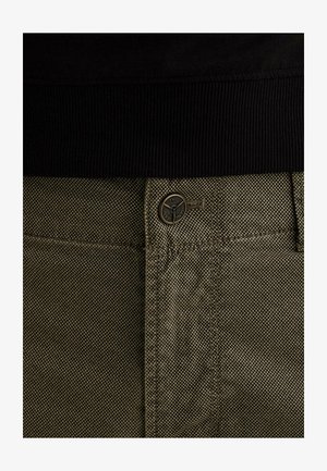 Detailný záber na khaki nohavice s textúrou, čiernym pásom a predným zapnutím s gombíkom s logom značky.