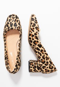 Chaussures à talons bas en imprimé léopard avec un bout légèrement arrondi, surface texturée ressemblant à de la fourrure, et motif tacheté marron-noir sur un fond beige.