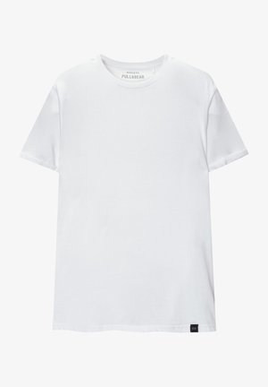 Weißes Muskel-fitt T-Shirt aus Baumwolle. Rundhals, kurze Ärmel, glatte Textur. Kleines schwarzes Logo-Tag am Saum. Schlichtes Design.