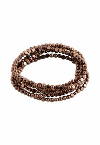 Eine gewundene Armbänder aus mehreren Strängen glänzender, facettierter metallisch brauner Perlen vor einem weißen Hintergrund.