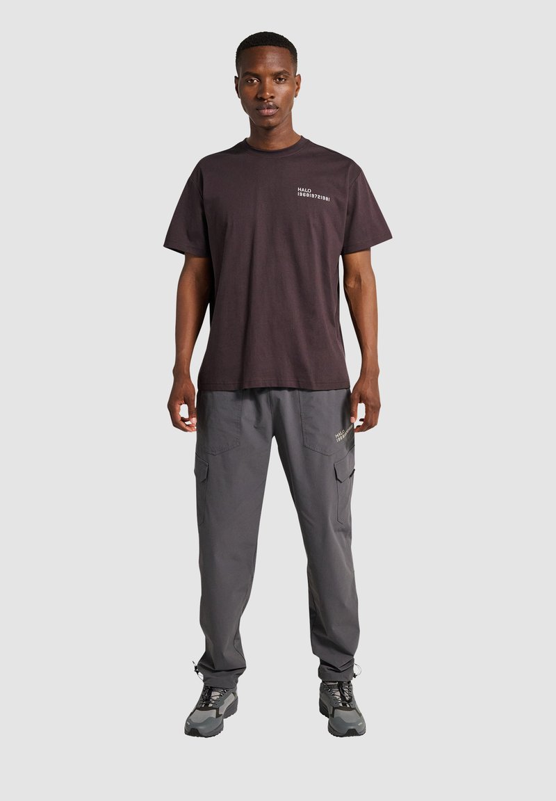 Sort bomulds T-shirt med et lille hvidt grafik på brystet, parret med mørkegrå cargo-bukser med sidelommer og diskret branding.