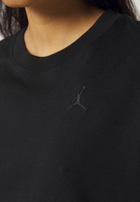 Maglietta in cotone nera con collo a giro e un logo Jumpman nero testurizzato ricamato sul lato sinistro del petto.