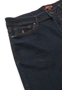Jeans de mezclilla azul oscuro con un diseño de cinco bolsillos, costuras naranjas en contraste y un cierre de botón en la cintura.