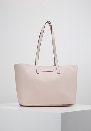 Lichtroze leren totebag met twee schouderbanden en een klein, centraal geplaatst DKNY-logo aan de voorkant, tentoongesteld op een wit voetstuk.