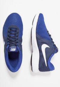 Zapatillas Nike Revolution 4 en azul marino, con una parte superior de malla, acentos en blanco del swoosh y una suela acolchada con patrones texturizados.
