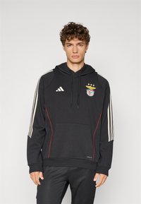 Fekete kapucnis pulóver fehér csíkokkal az ujjakon, piros kiegészítőkkel és elülső zsebbel. A mellkason a Benfica logó található, légáteresztő anyagból készült.