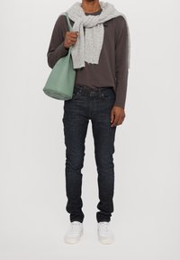 Długa szara koszula z długim rękawem, jasnoszary szalik, niebieskie dżinsy i białe trampki. Zielona torba na ramię z okrągłym dnem. Prosty i casualowy wygląd.