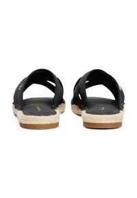 Sorte åpne sandaler med kryssende stropper, jute-lignende såler og en glatt svart fotbrett. Har en tan gummisåle for grep.