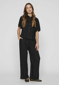 Black, loose-fitting matching set featuring a short-sleeve button-up top and wide-leg trousers. Both pieces have a soft texture and relaxed silhouette.