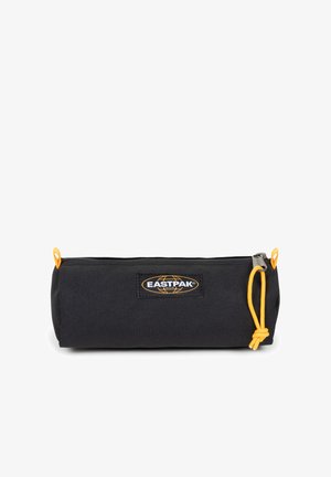 Estuche de lápices de lona negra con una cremallera amarilla, con un logo de Eastpak en el lateral y un diseño cilíndrico simple.