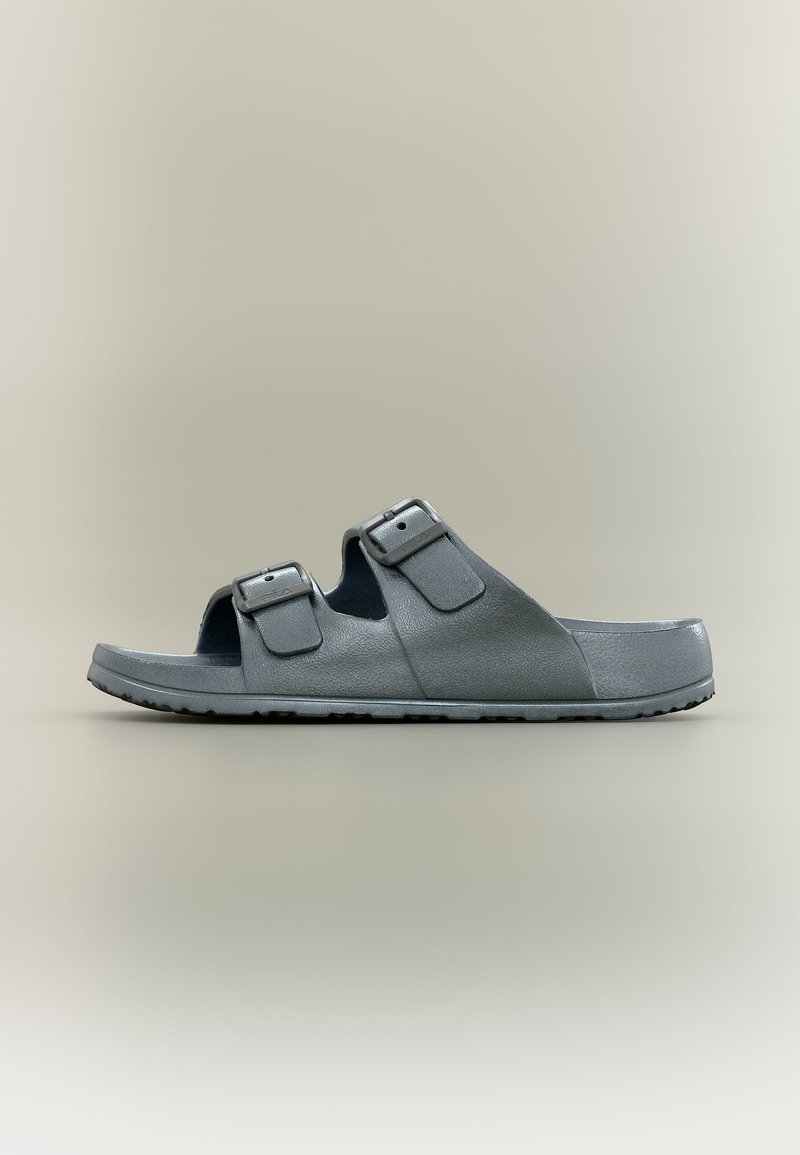 Sandale slide gris foncé avec deux brides réglables à boucle et semelle texturée, vue de profil sur un fond neutre.