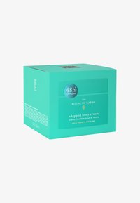En teal-färgad låda som innehåller vispad kroppskräm, med etiketten "48 timmars fuktighet", prydd med vit text och detaljer, med doft av lotusblomma och vitt te.