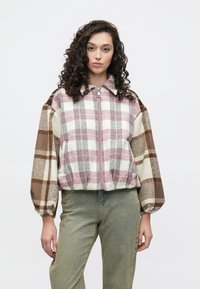 Ruuduline bomberjakk roosas, kreemis ja pruunis. Omab esitampliga lukku, laia varrukaid ja lühendatud ääreosa. Valmistatud tekstureeritud kangast.