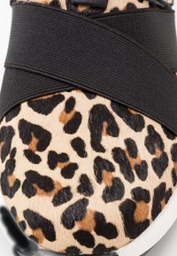 Scarpa slip-on con stampa leopardo, caratterizzata da una tomaia in tessuto testurizzato e una larga fascia elastica nera sul davanti, con suola in gomma bianca.