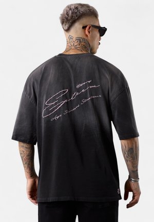 Schwarzes, übergroßes T-Shirt mit einem Farbverlauf-Design, kurzen Ärmeln und pinkem, gesticktem Text auf der Rückseite. Baumwollmaterial mit einem lockeren Schnitt.