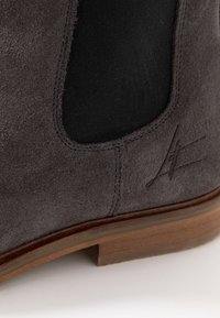 Stivaletto alla caviglia in suede grigio scuro con pannello laterale elastico nero e tacco in legno. Include un dettaglio logo stampato vicino al tacco.