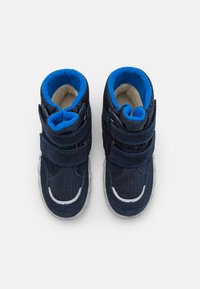 Zapatillas altas de color azul marino con dos correas ajustables de velcro, forro de felpa y costuras de acento blancas en una parte superior de tejido texturizado.