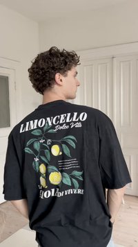 T-shirt oversized preta com um gráfico de limão e folha, com o texto "Limoncello Dolce Vita" em fonte branca em negrito nas costas.