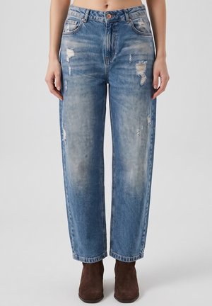 Blue high-waist straight-leg jeans with distressed details worn with brown ankle boots on a person standing against a neutral background.