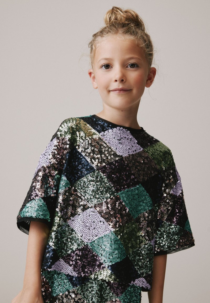 Paljettopp med ett geometriskt diamantmönster i grönt, lila, svart och silver, med korta ärmar och rund halsringning.