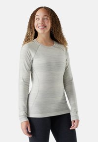 Lys grå langærmet træningsshirt med teksturerede striber, raglanærmer og rund halsudskæring. Har en lille logoaccent på ærmet.