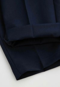 Granatowy plisowany materiał o gładkiej fakturze, z mankietowanym dołem i ukośnym wzorem tkania dla nadającego strukturę designu.