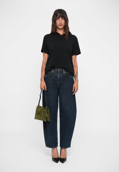 Svart polo skjorta, lösa blå jeans, grön väska med svart rem, svarta spetsiga klackar. Tatueringar synliga på armarna. Enkel, tight passform.