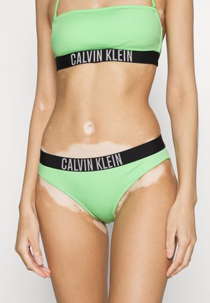 Světlý zelený bikiny horní díl s nastavitelnými ramínky, doplněný o odpovídající zelené bikiny kalhotky s černým páskem označeným "CALVIN KLEIN."