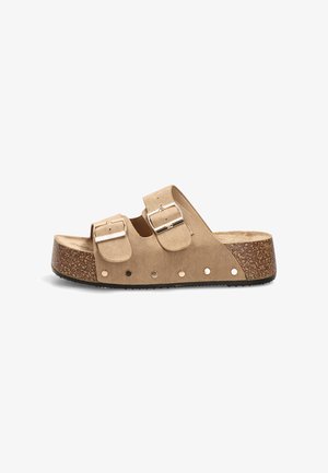 Sandalia tipo slide de ante beige con dos hebillas plateadas ajustables, suela plataforma de corcho y suela exterior negra texturizada.