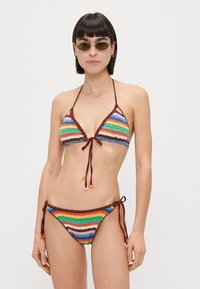Bikini en crochet multicolore avec un haut triangulaire et un bas à liens sur les côtés. Présente des rayures horizontales aux couleurs vives et des accents en brun.