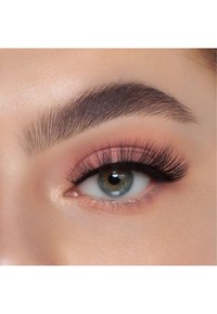 Nära bild av ett grönt öga med mörka fransar och subtilt rosa ögonskugga. Ögonbrynet är väldefinierat med en naturlig form och textur.