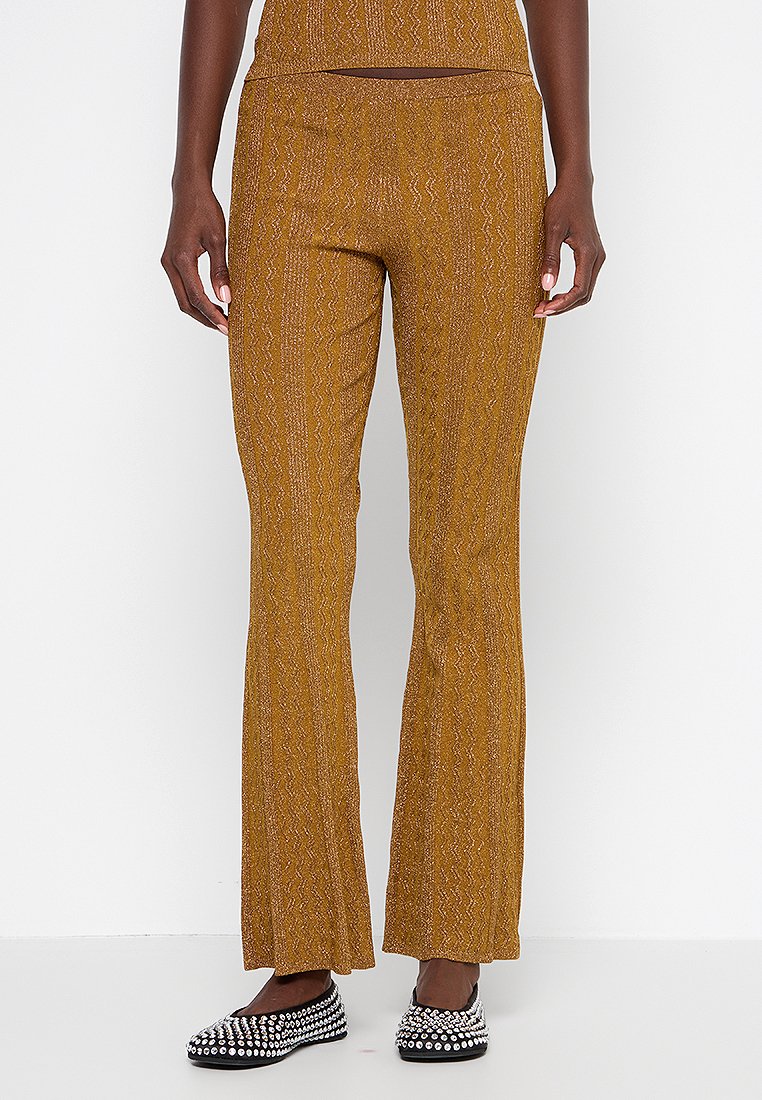 Braune Strick-Hosen mit einem strukturierten Zickzackmuster und hohem Taillen-Design. Kombiniert mit schwarzen, mit Nieten besetzten Ballerinas.