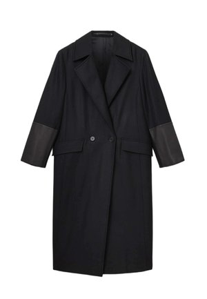Czarny płaszcz o wyraźnie zarysowanej sylwetce, z wyłogami typu notch, dwurzędowym zapięciem oraz skórzanymi akcentami na rękawach i kieszeniach.