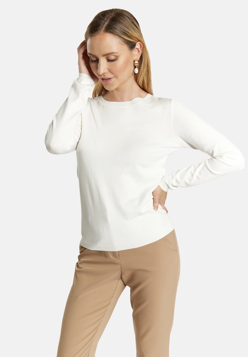 Witte langekorte top met een ronde halslijn, zachte textuur en een aansluitend ontwerp, gecombineerd met tan broek. Geen patronen of extra accenten.